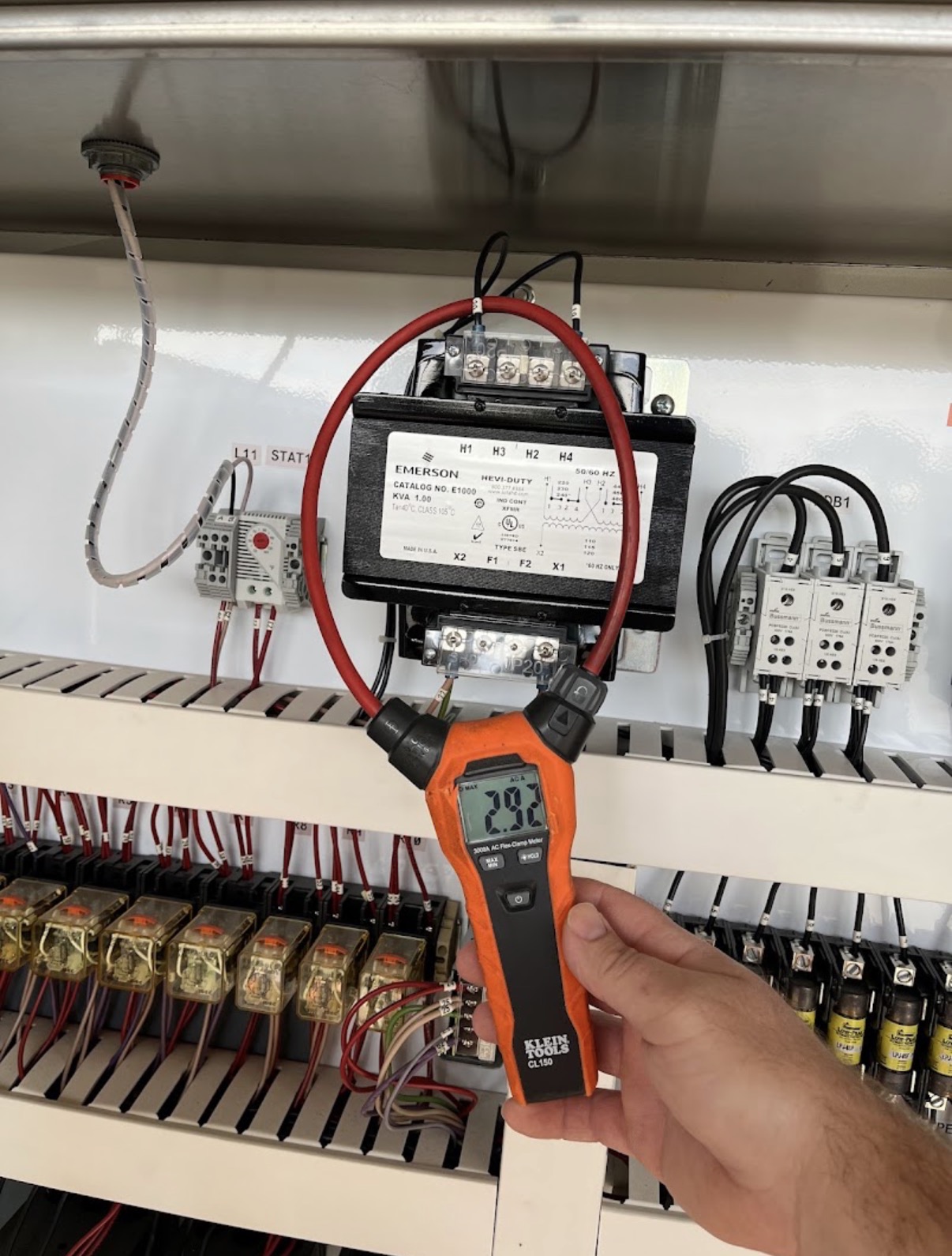 Electrical technician testing commercial electrical equipment with a clamp meter